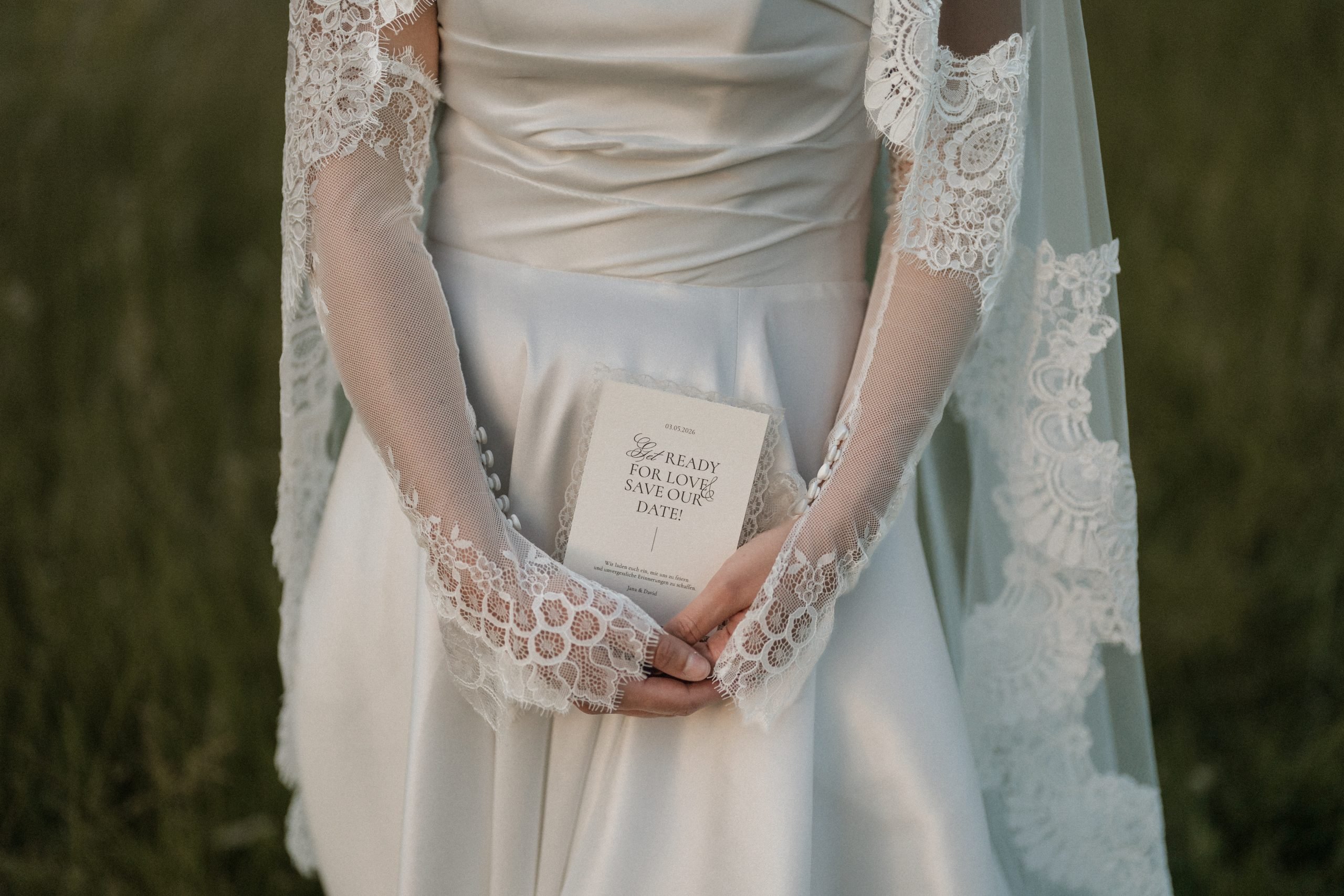 Save the Date Karte mit Lace Element Das Bild zeigt eine moderne Hochzeitspapeterie in der Hand der Braut